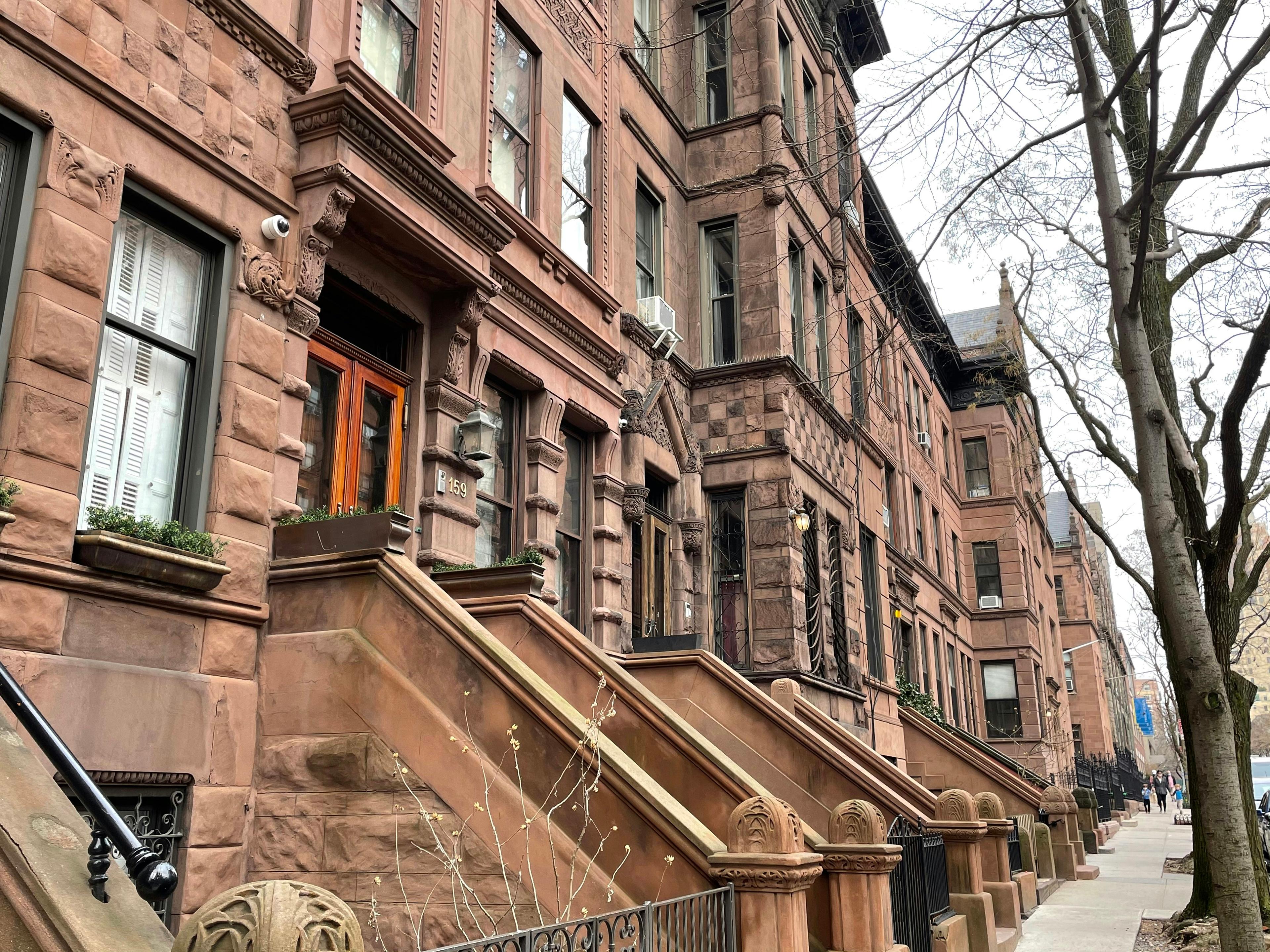 Upper West Side brownstones in a row with stone stoops, ornate cornices and bare winter trees